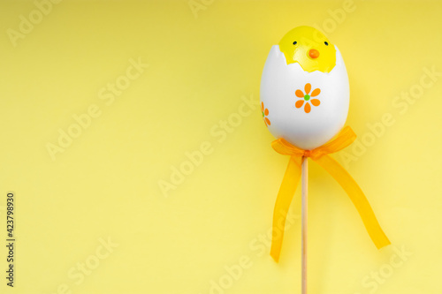 Colorful Easter egg chick on yellow pastel background