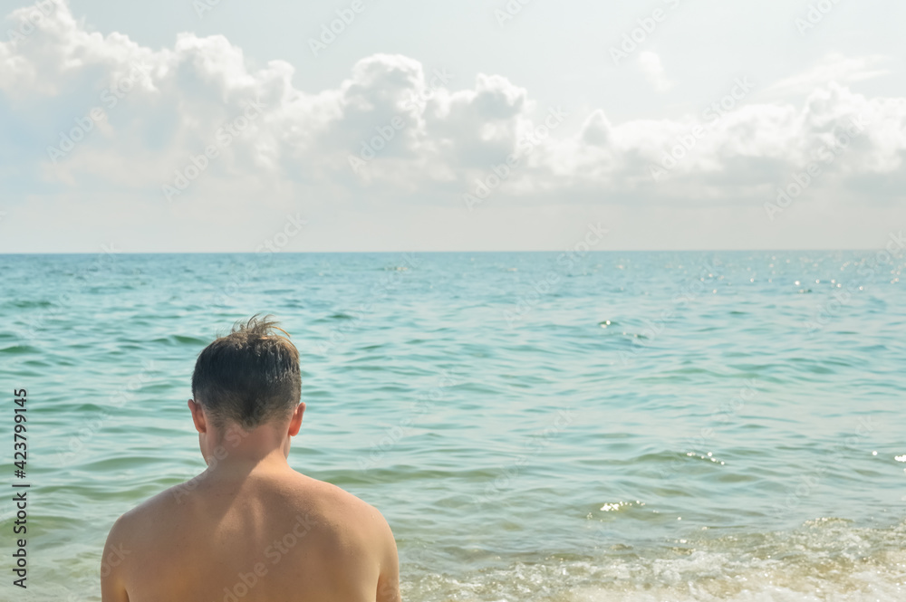 Lonely young man on summer beach against calm sea background. Lonely young man on summer beach against calm sea background.
