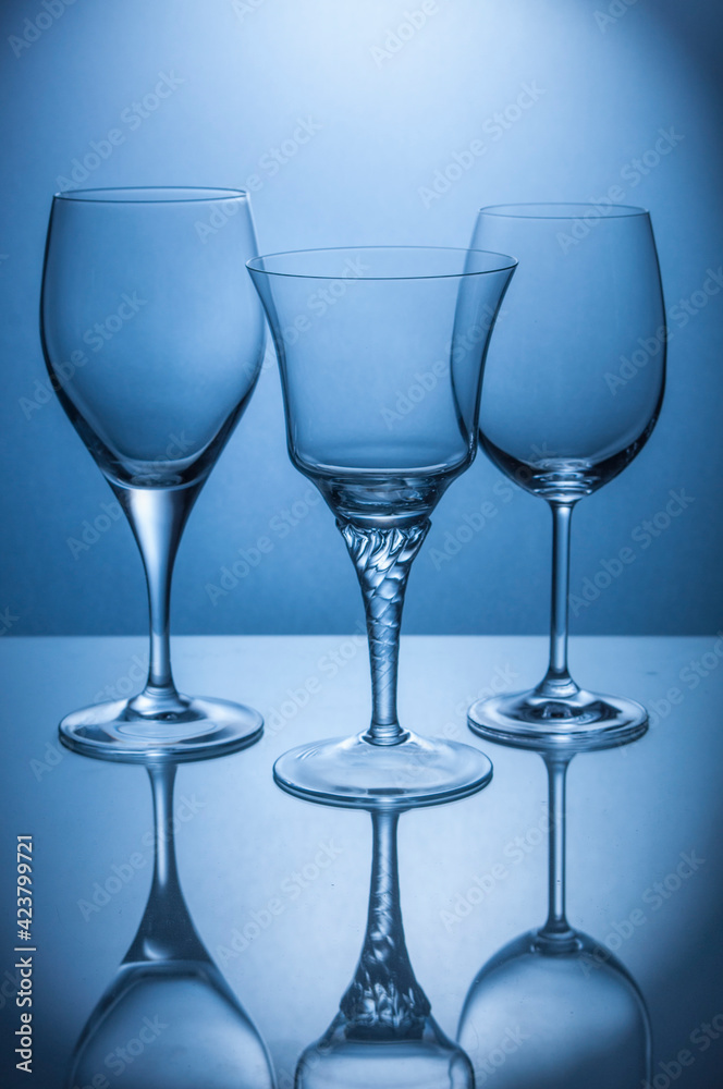 three crystal glasses on blue illuminated transparent background