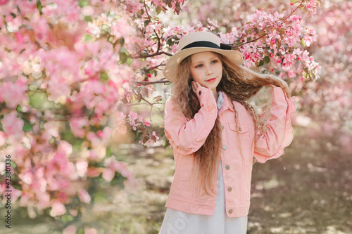 Nice blonde girl play with hair in blooming apple garden with pink colored big flowers. Dreamy picture. Horizontal photo with copy space
