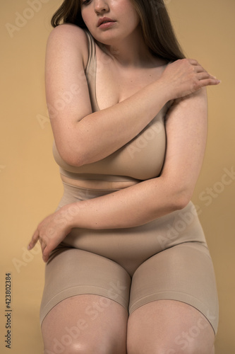 Plus size woman with folds at her body demonstrating her body while posing