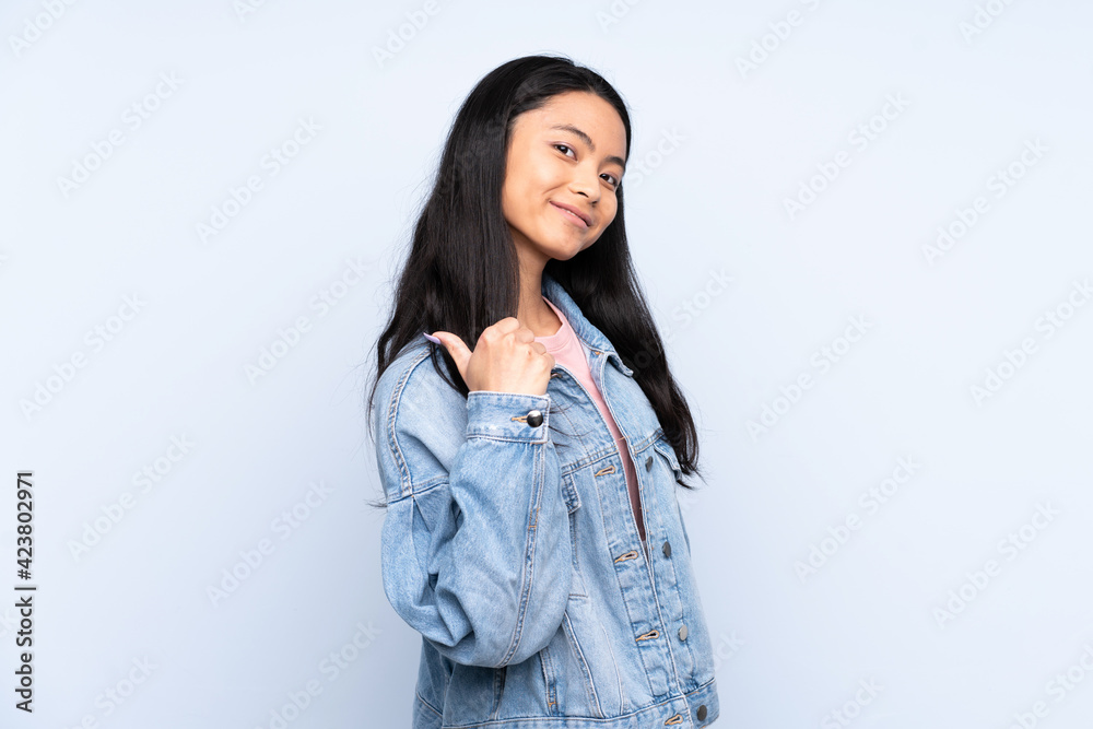 Teenager Chinese woman isolated on blue background proud and self-satisfied
