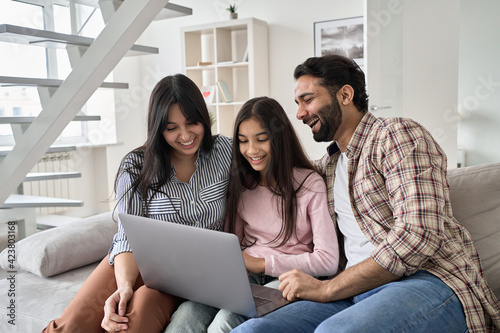 Fotografie Happy indian family with child daughter having fun using laptop computer at home
