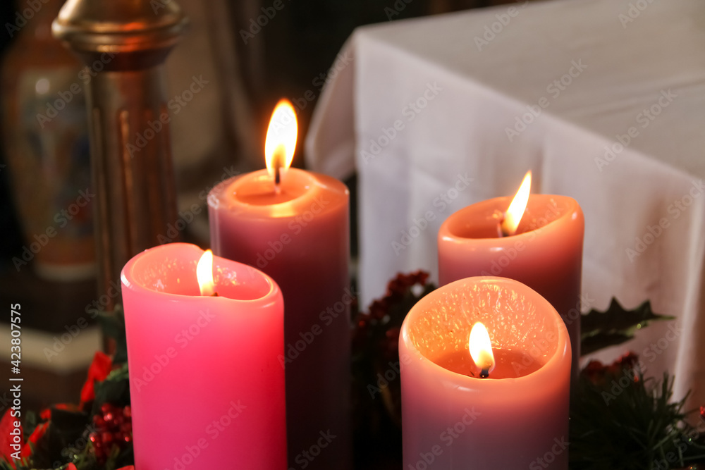 Four purple candles lit over an advent wreath for Sunday Mass in the church Four purple candles lit over an advent wreath for Sunday Mass in the church