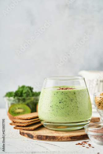 Detox green smoothie with kale, spinach and kiwi on a light gray slate, stone or concrete background. Top view with copy space.