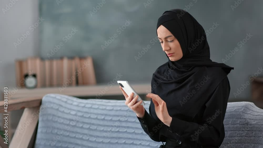 Pleasant Muslim lady in hijab chatting surfing internet use smartphone. Shot with RED camera in 4K Pleasant Muslim lady in hijab chatting surfing internet use smartphone. Shot with RED camera in 4K