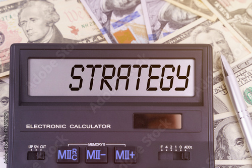 On the table are dollars and a calculator on the electronic board which says STRATEGY