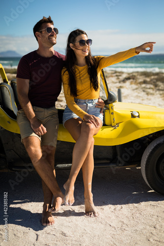 Happy caucasian couple sitting on beach buggy by the sea embracing