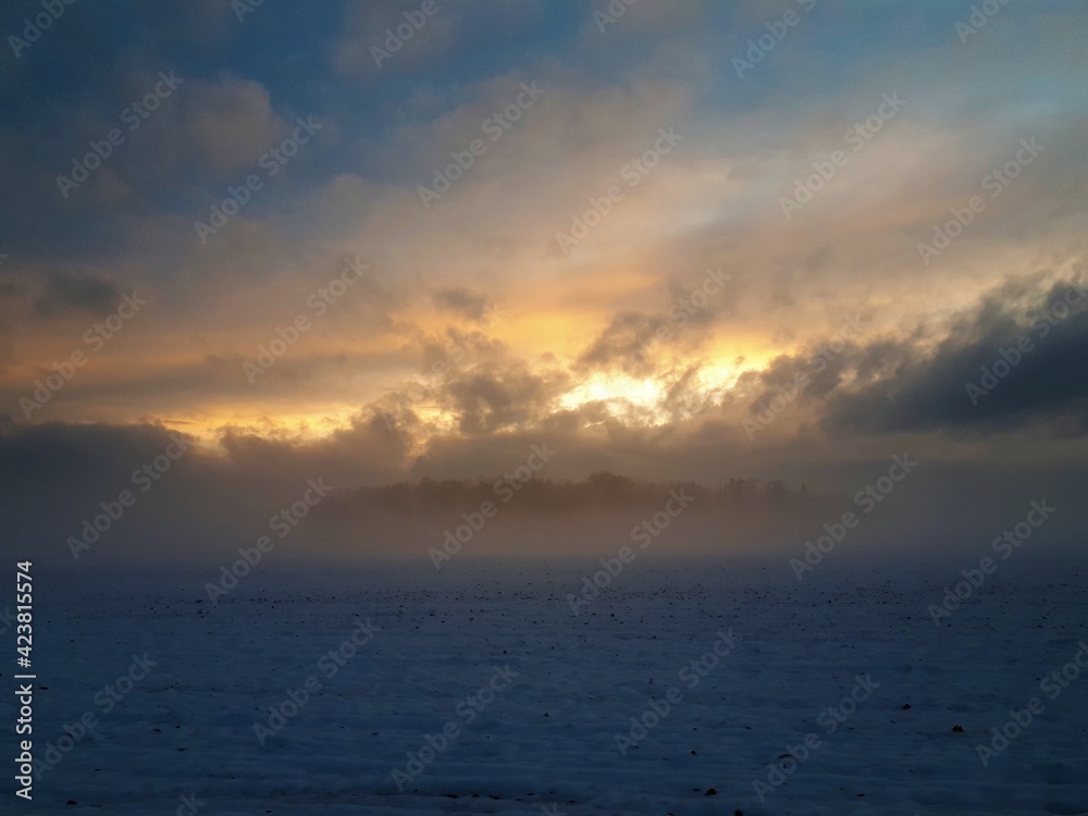Landscape covered in snow and fog and clouds at sunset