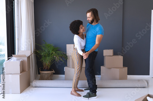 Happy diverse couple moving house smiling and dancing