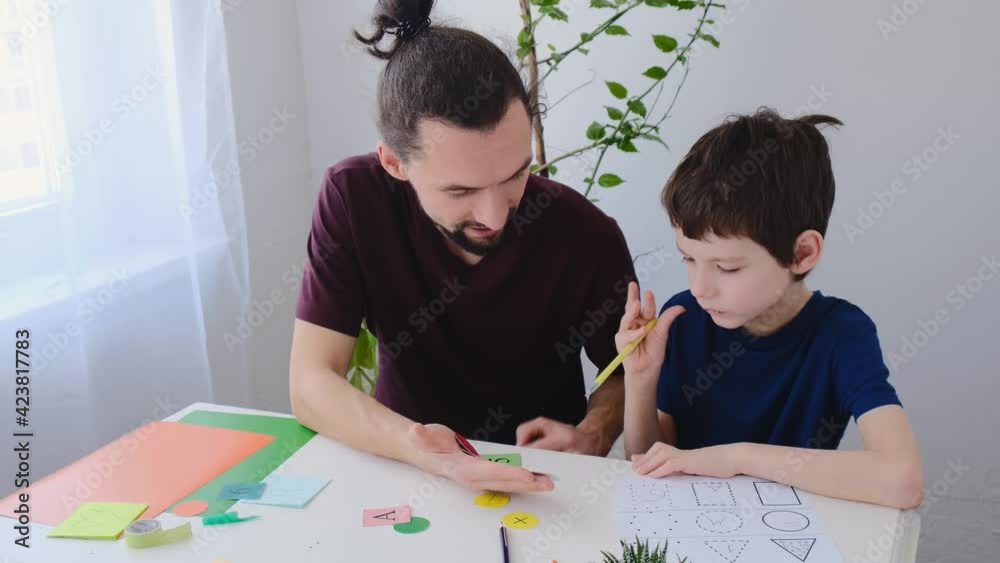 Happy autism boy during therapy with his father, learning together. Autism therapy at home concept Happy autism boy during therapy with his father, learning together. Autism therapy at home concept
