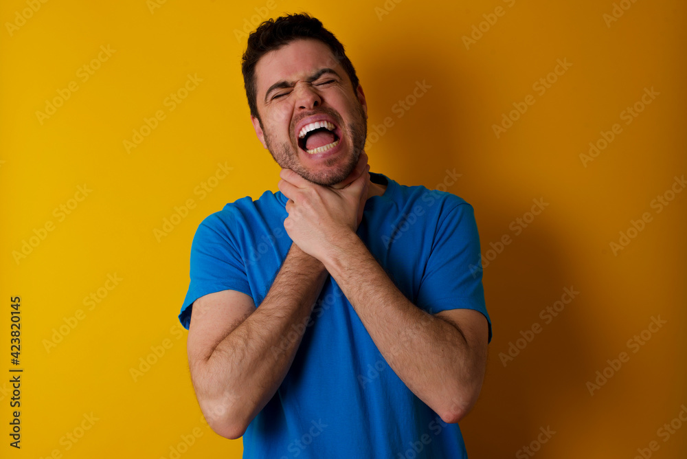 young handsome caucasian man wearing blue t-shirt against yellow background shouting suffocate because painful strangle. Health problem. Asphyxiate and suicide concept. young handsome caucasian man wearing blue t-shirt against yellow background shouting suffocate because painful strangle. Health problem. Asphyxiate and suicide concept.