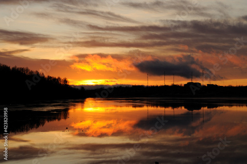 A brightly fiery sunset on Lake Semyonovskoye. Reflection of floating clouds and sun in the lake. Beautiful landscape in nature. Semenovskoe lake, Murmansk © алексей синяков