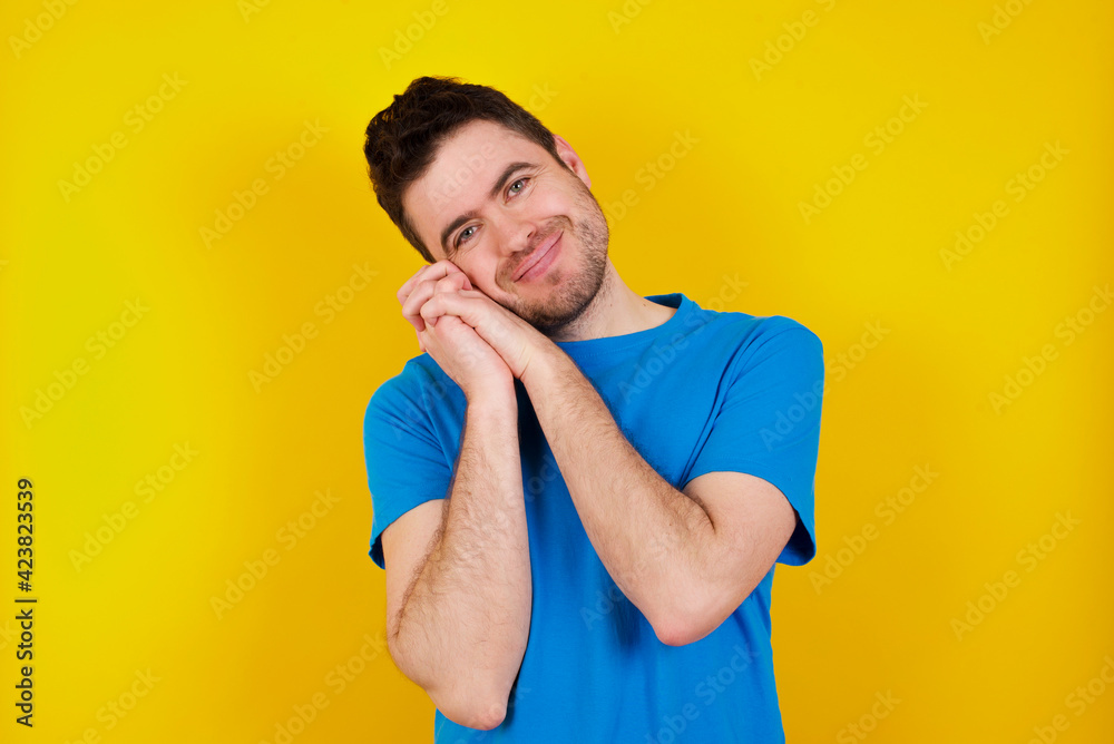 Offended dissatisfied young handsome caucasian man wearing blue t-shirt against yellow background with moody displeased expression at camera being disappointed by something