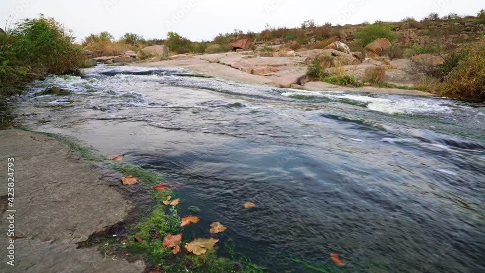 A small shining stream flows among smooth wet and dark stones A small shining stream flows among smooth wet and dark stones
