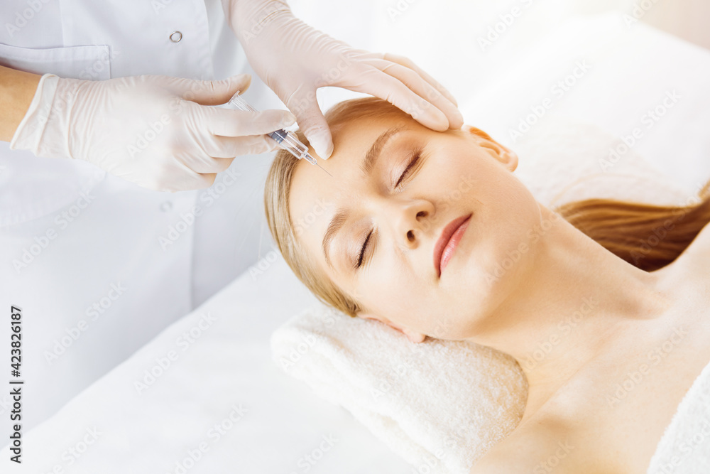 Beautician doctor doing beauty procedure with syringe to caucasian female face. Cosmetic medicine and surgery, beauty injections concept