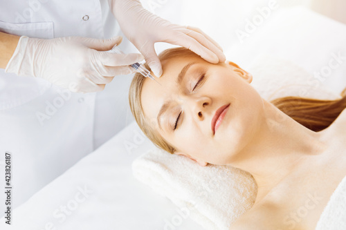 Beautician doctor doing beauty procedure with syringe to caucasian female face. Cosmetic medicine and surgery, beauty injections concept