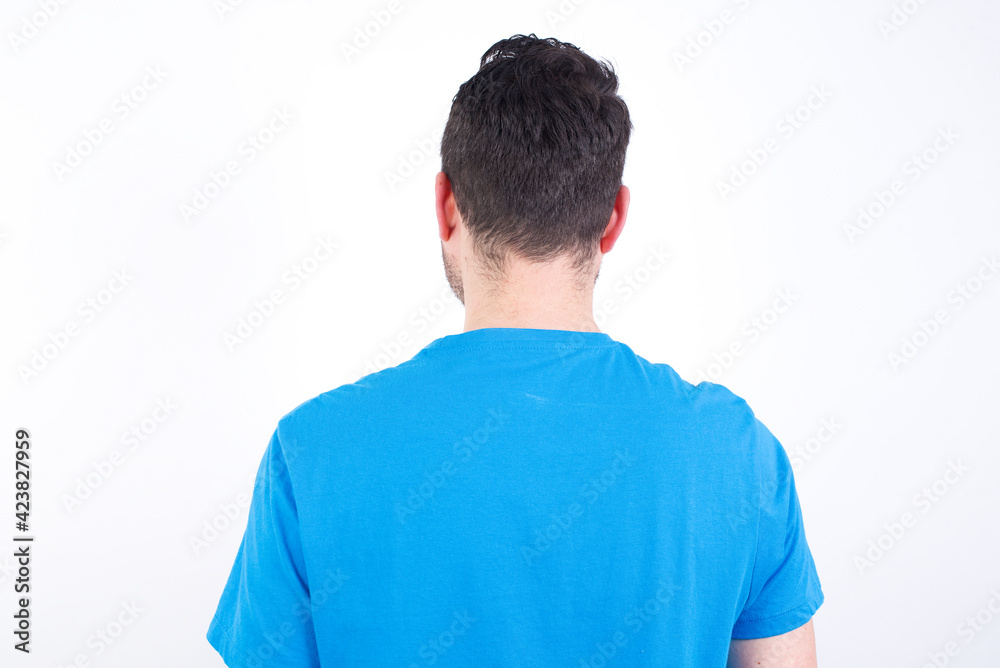 The back view of a young handsome caucasian man wearing blue t-shirt against white background . Studio Shoot. The back view of a young handsome caucasian man wearing blue t-shirt against white background . Studio Shoot.