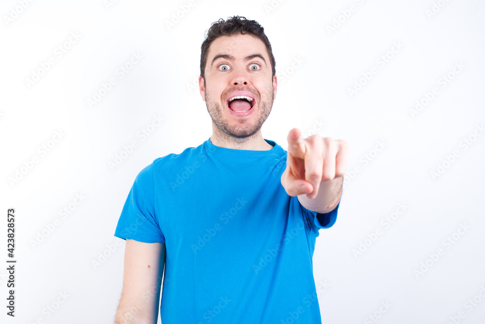 Excited positive young handsome caucasian man wearing white t-shirt against white background points index finger directly at you, sees something very funny. Wow, amazing Excited positive young handsome caucasian man wearing white t-shirt against white background points index finger directly at you, sees something very funny. Wow, amazing