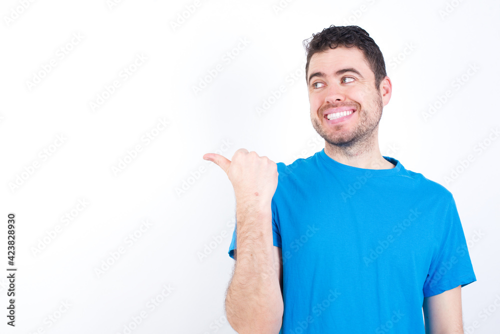 young handsome caucasian man wearing white t-shirt against white background points away and gives advice demonstrates advertisement young handsome caucasian man wearing white t-shirt against white background points away and gives advice demonstrates advertisement