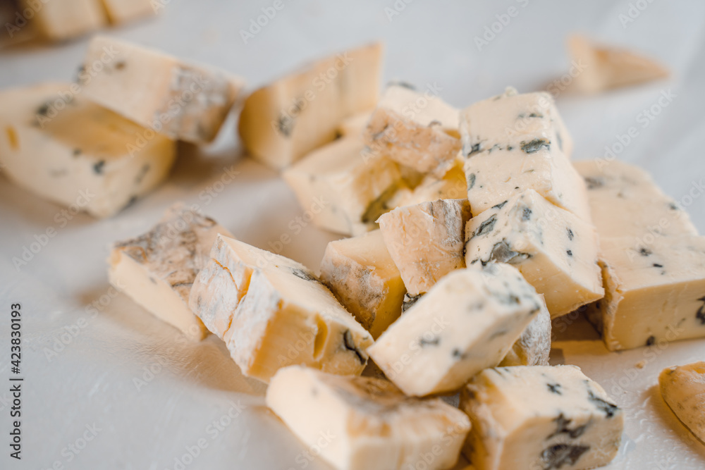 Mix of cheeses on plate. Slicing blue cheese dorblu, gorgonzola, roquefort. French gourmet traditional cuisine.