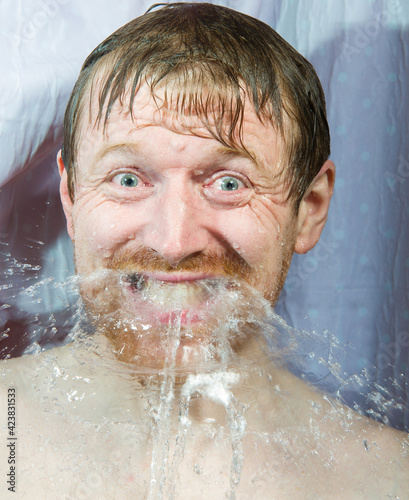 Whte man under shower water streams, dynamic face with beard