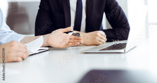 Unknown business people using laptop computer at the desk in modern office. Businessman or male entrepreneur is working with his colleague. Teamwork and partnership concept