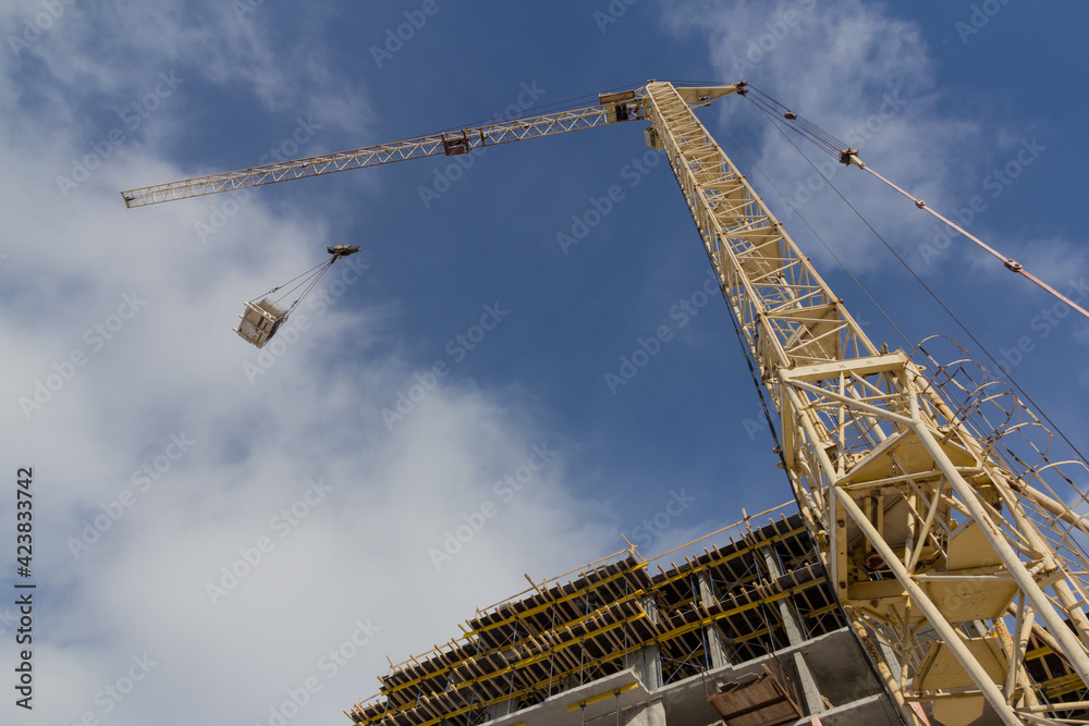 Tower crane on the background of the facade of the building. Lifting mechanism on the construction site