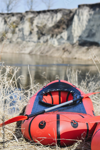 Red packraft rubber boat on the river bank. Selective focus. Active lifestile concept. photo