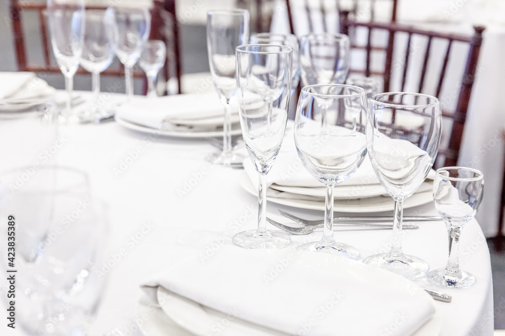 Fancy table set for dinner with napkin glasses in restaurant, luxury interior background. Wedding elegant banquet decoration and items for food arranged by catering service on white tablecloth table. Fancy table set for dinner with napkin glasses in restaurant, luxury interior background. Wedding elegant banquet decoration and items for food arranged by catering service on white tablecloth table.