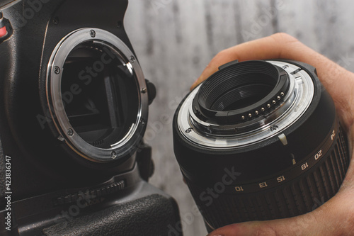 the photographer attaches the lens to the SLR camera