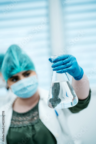Woman holds medical flask with clear liquid