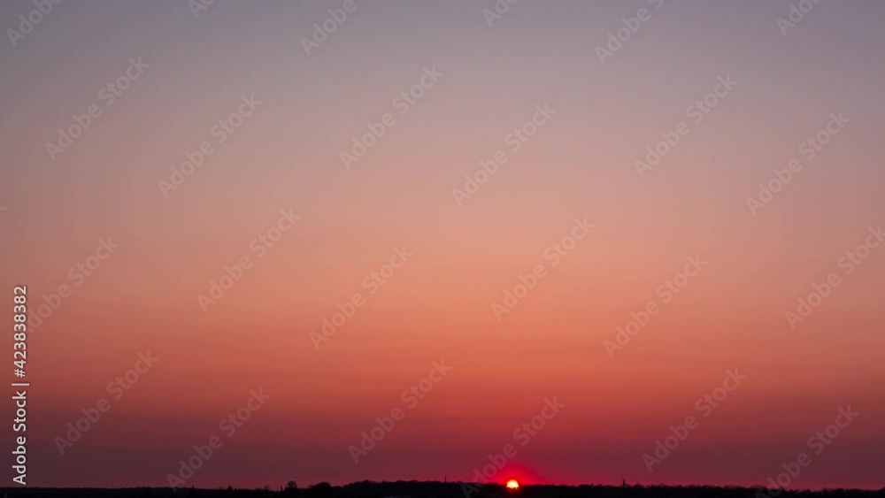 Timelapse crimson sunset with small clouds. The sun goes down behind the trees Timelapse crimson sunset with small clouds. The sun goes down behind the trees