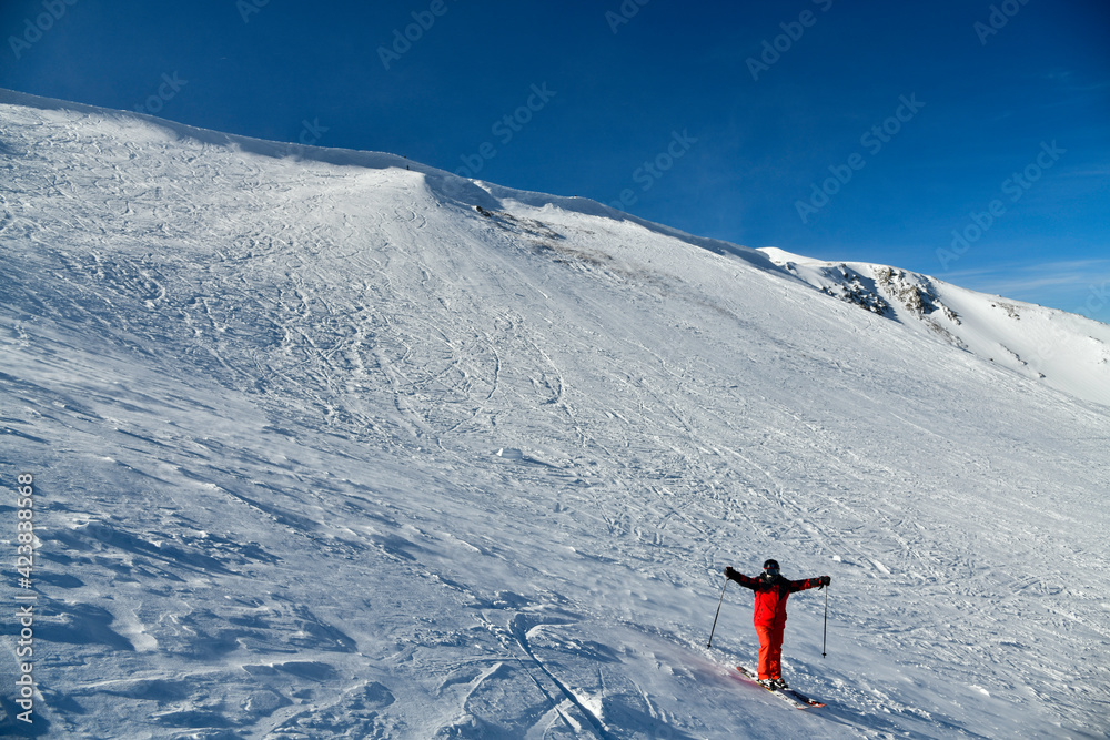 Man wearing bright red suit skiing on snowy backcountry bowl area. Extreme winter sports. Breckenridge, Colorado at Emperial bowl area