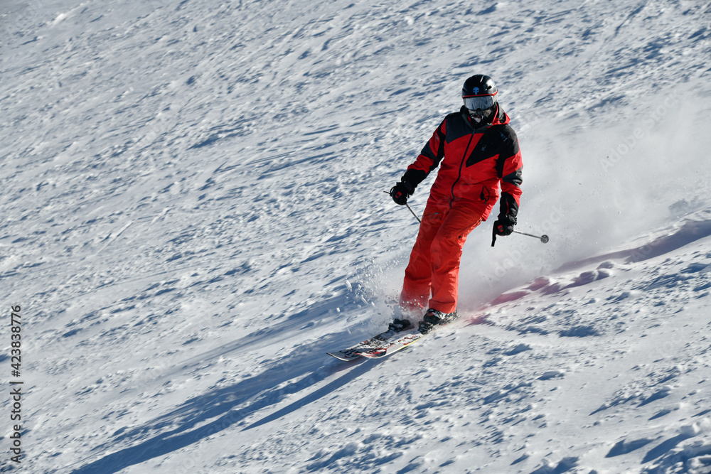 Skier in red suit going down the slope on a sunny day at Breckenridge Ski resort, CO