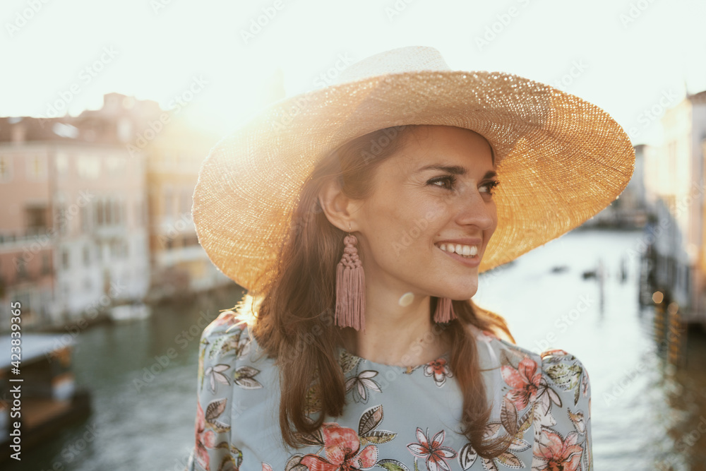 smiling stylish woman in floral dress having walking tour