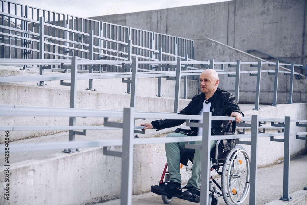 Disabled man in wheelchair on the beginning of the ramp. Independent in transport.