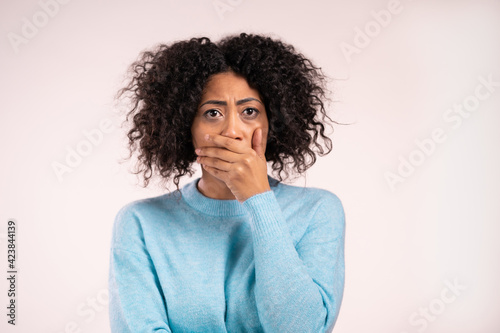 Portrait of african unpleasantly surprised and shocked girl on white studio background. Woman receiving bad news. She expresses sympathy and regret.