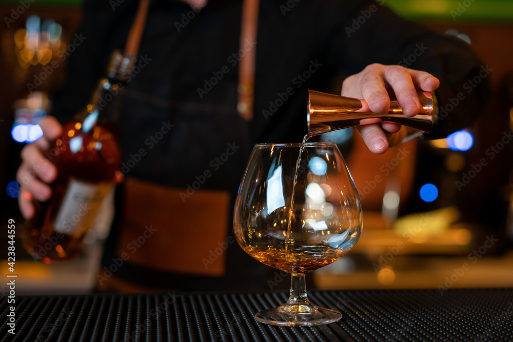 Waiter pouring cognac into the cup