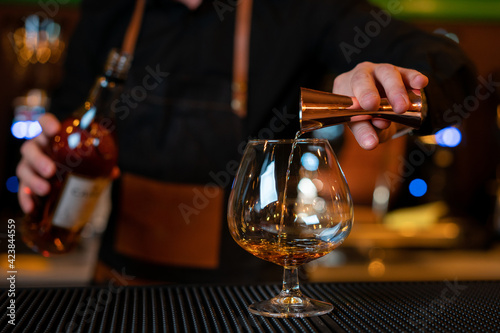 Waiter pouring cognac into the cup