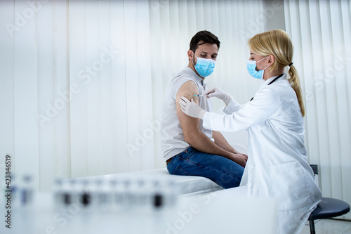 Nurse giving young caucasian man vaccine shot during corona virus pandemic. Stop COVID-19.