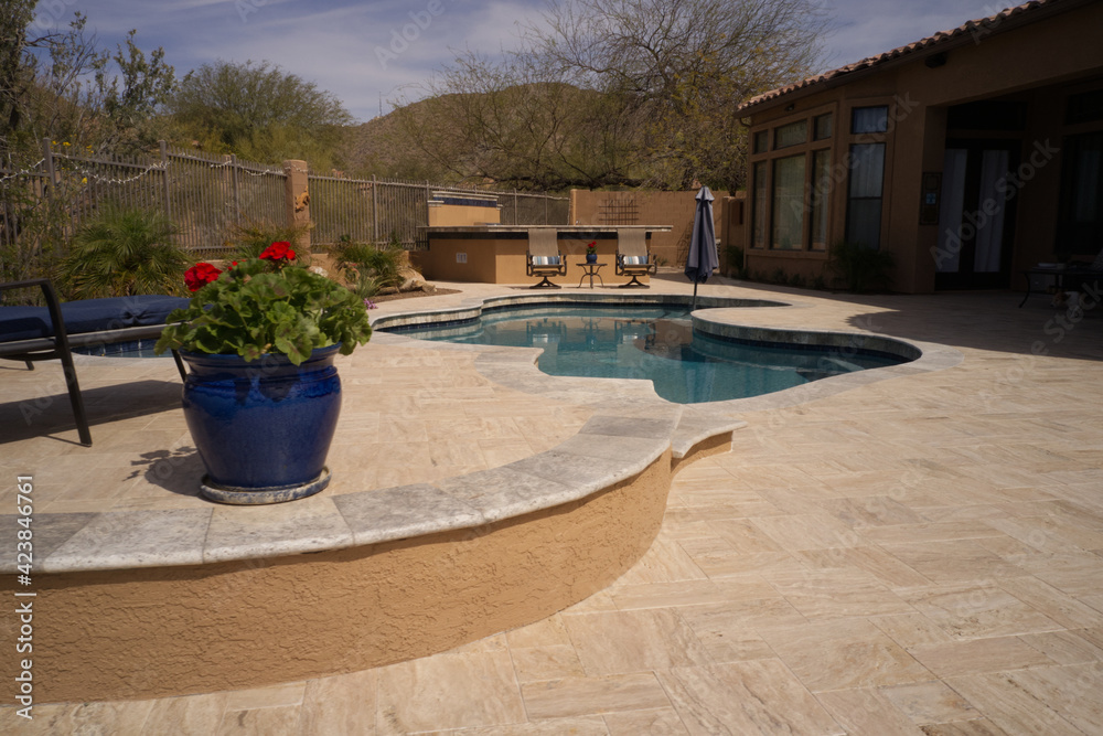 Fototapeta premium A desert landscaped back yard in Arizona featuring travertine tile.