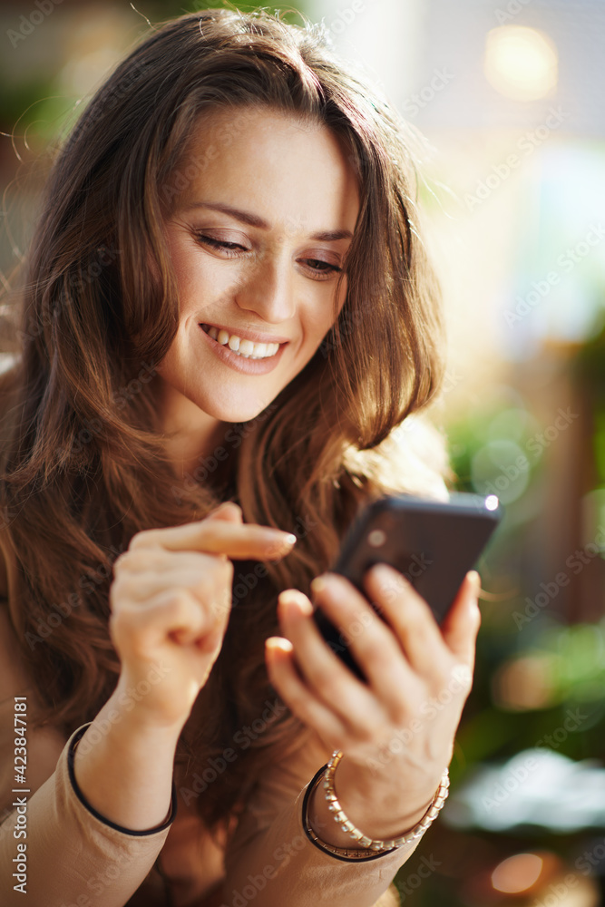 smiling woman in sunny day sending text message using phone smiling woman in sunny day sending text message using phone
