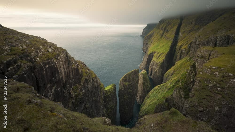 Time lapse of cliff and rock formation Dunnesdrangar and clouds over the ocean, birds flying arouind, Vagar Faroe Islands
