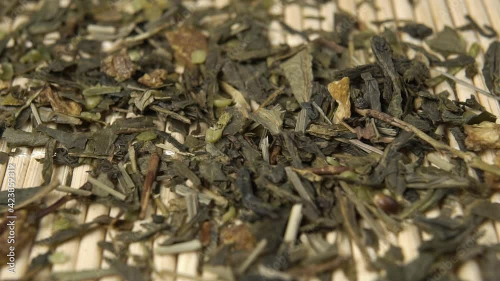 Green tea with hemp and rose bush close-up. Fall in slow motion on a bamboo mat. Dried leaves of a medicinal herbal treatment with marijuana. Macro Green tea with hemp and rose bush close-up. Fall in slow motion on a bamboo mat. Dried leaves of a medicinal herbal treatment with marijuana. Macro