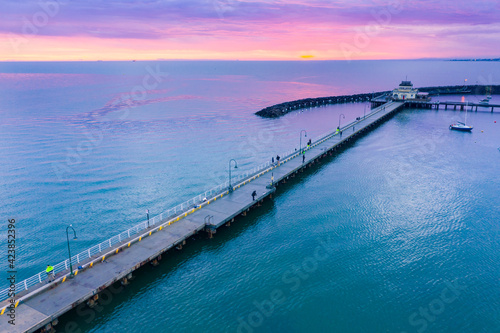 Aerial view of a dramatic purple sunset over a coastal jetty and breakwater