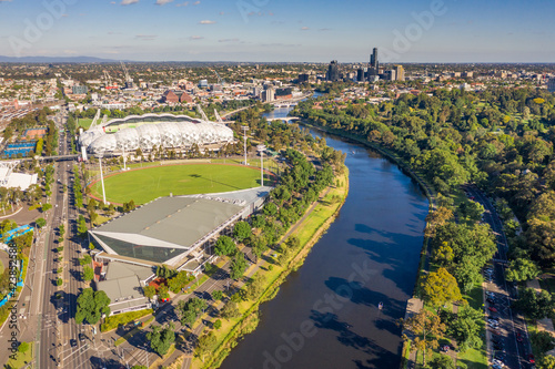 Aerial view of a wide river winding through a city with parkland and sporting facilities along side