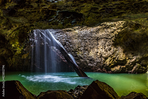 Water flowing through natural arch into underground cave photo