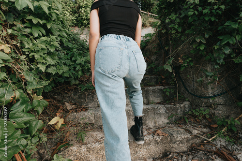 Back part of a woman wearing mom jeans surrounded by plants and modern style photo