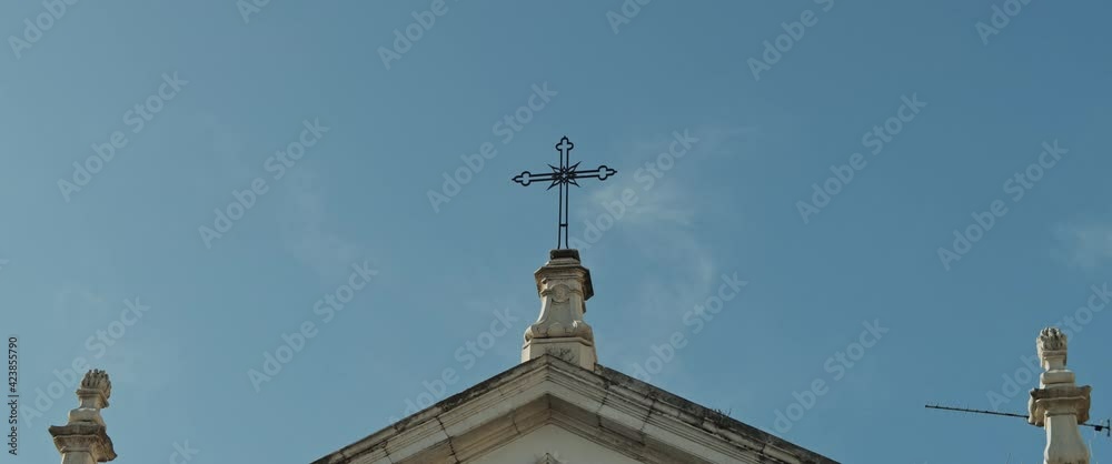 An ancient catholic church with cross on top against the blue sky background. Slow motion. An ancient catholic church with cross on top against the blue sky background. Slow motion.